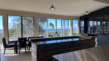 A modern kitchen with large windows, a wooden island, and a view of the ocean.