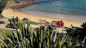 Una spiaggia con acque cristalline, un litorale roccioso e una passerella in legno.