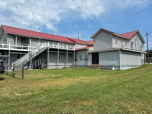 A two-story building with a red roof, a covered porch, and a staircase leading to a balcony. - RiverView Apartment in  Ravenswood at the Historic Victoria Inn Apartments (Ravenswood)