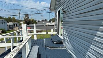 A wooden deck with a bench, a white fence, and a house with a grey exterior.