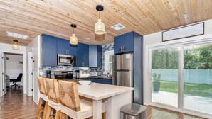 A modern kitchen with blue cabinets, stainless steel appliances, and a large island.