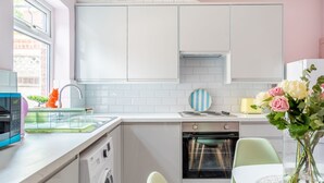 A modern kitchen with white cabinets, a dishwasher, an oven, and a dining area with a table and chairs.