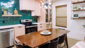 Een moderne keuken met een houten eettafel, zwarte stoelen en een neonbord aan de muur.