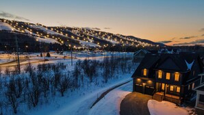 A snow-covered landscape with a lit house and a winding road. - Bright, spacious, amazing view at a prime location (The Blue Mountains)