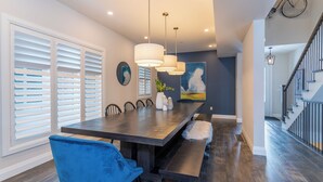 A modern dining area with a long table, blue chairs, and pendant lighting. - Bright, spacious, amazing view at a prime location (The Blue Mountains)