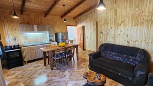 A cozy wooden interior with a dining area, sofa, and kitchen. - Fully equipped cabins, on the jungle route on the way to the Moconá Falls. (El Soberbio)