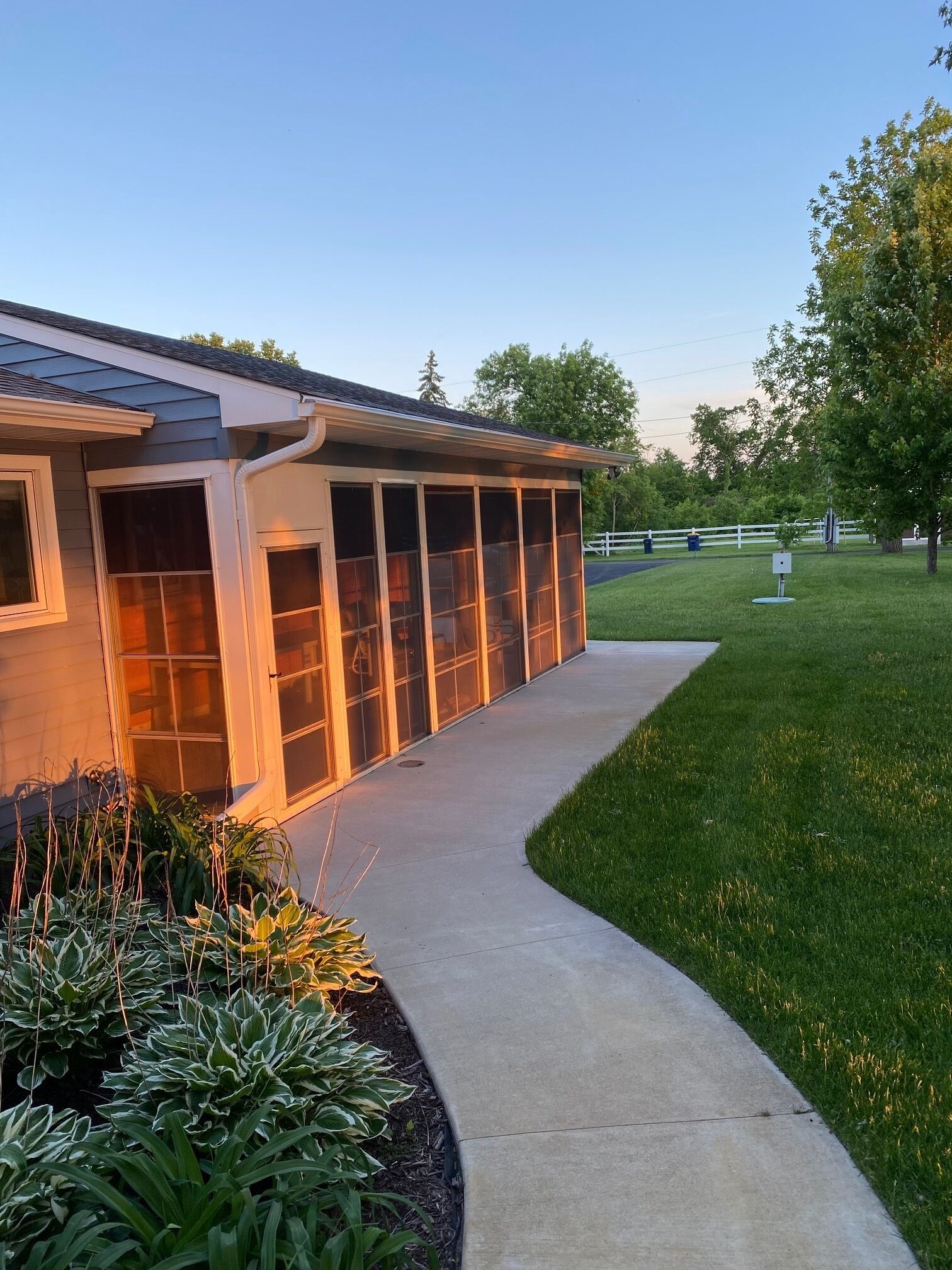 A building with a covered outdoor area, a concrete pathway, and a grassy lawn.