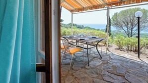 Eine Terrasse im Freien mit Esstisch, Steinböden und Blick auf das Meer.