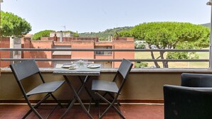 A balcony with a table set for two, overlooking a residential area with trees and buildings. - Bortoli by Interhome (Castiglione della Pescaia)