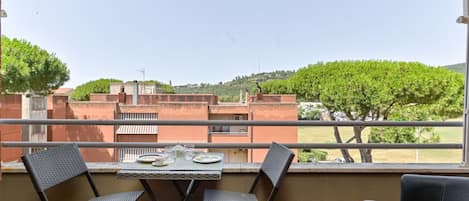 A balcony with a table set for two, overlooking a residential area with trees and buildings.