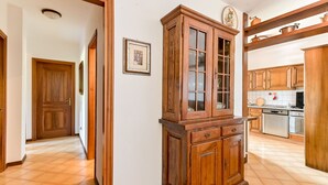 A hallway with a wooden cabinet, a door, and a kitchen area with cabinets and appliances. - Bortoli by Interhome (Castiglione della Pescaia)