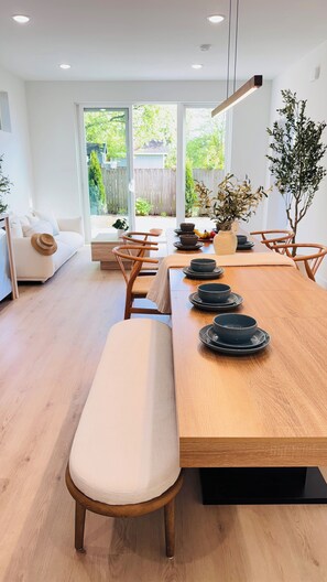 A modern dining area with a wooden table set for four, surrounded by wooden chairs. - Brand New Luxury Seattle Retreat (Seattle)