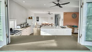 A modern kitchen with a gas stove, white cabinets, and a dining area with a table and chairs.