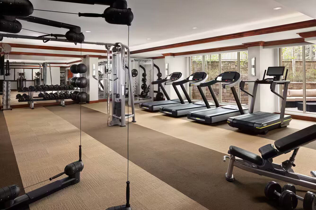 Une salle de sport équipée de tapis de course, d’appareils de musculation et de poids libres.