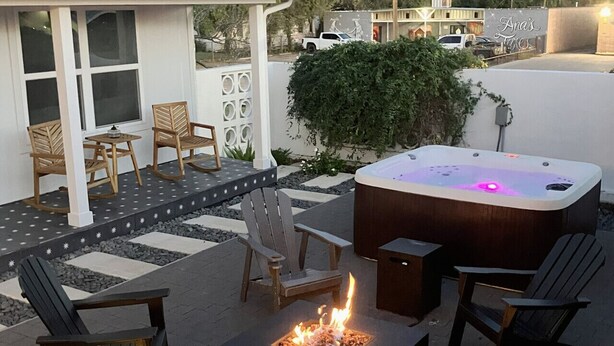 An outdoor patio with Adirondack chairs, a fire pit, and a hot tub.