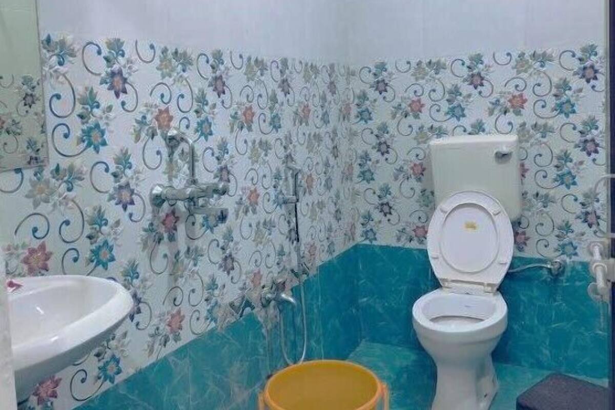 A bathroom with a toilet, sink, shower, and decorative floral tiles.