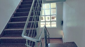 Una escalera con barandillas de metal que conduce a un rellano con una ventana.