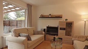 A living room with a sofa, a glass coffee table, a TV, and a wooden cabinet. - Apartment in Braunlage (Braunlage)