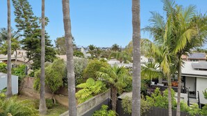 A residential area with tall palm trees, a fenced garden, and houses in the background. - Ocean-View 1BR Retreat w/ Large Private Terrace - Walk to Beach & Dining (Solana Beach)