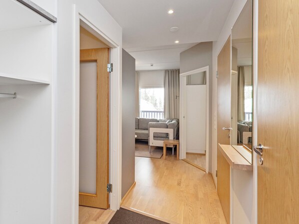 A hallway with a wooden door, a small table, and a sofa in the background.