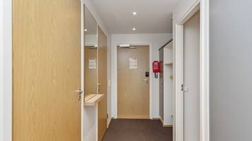 A hallway with wooden doors, a fire alarm, and a carpeted floor.
