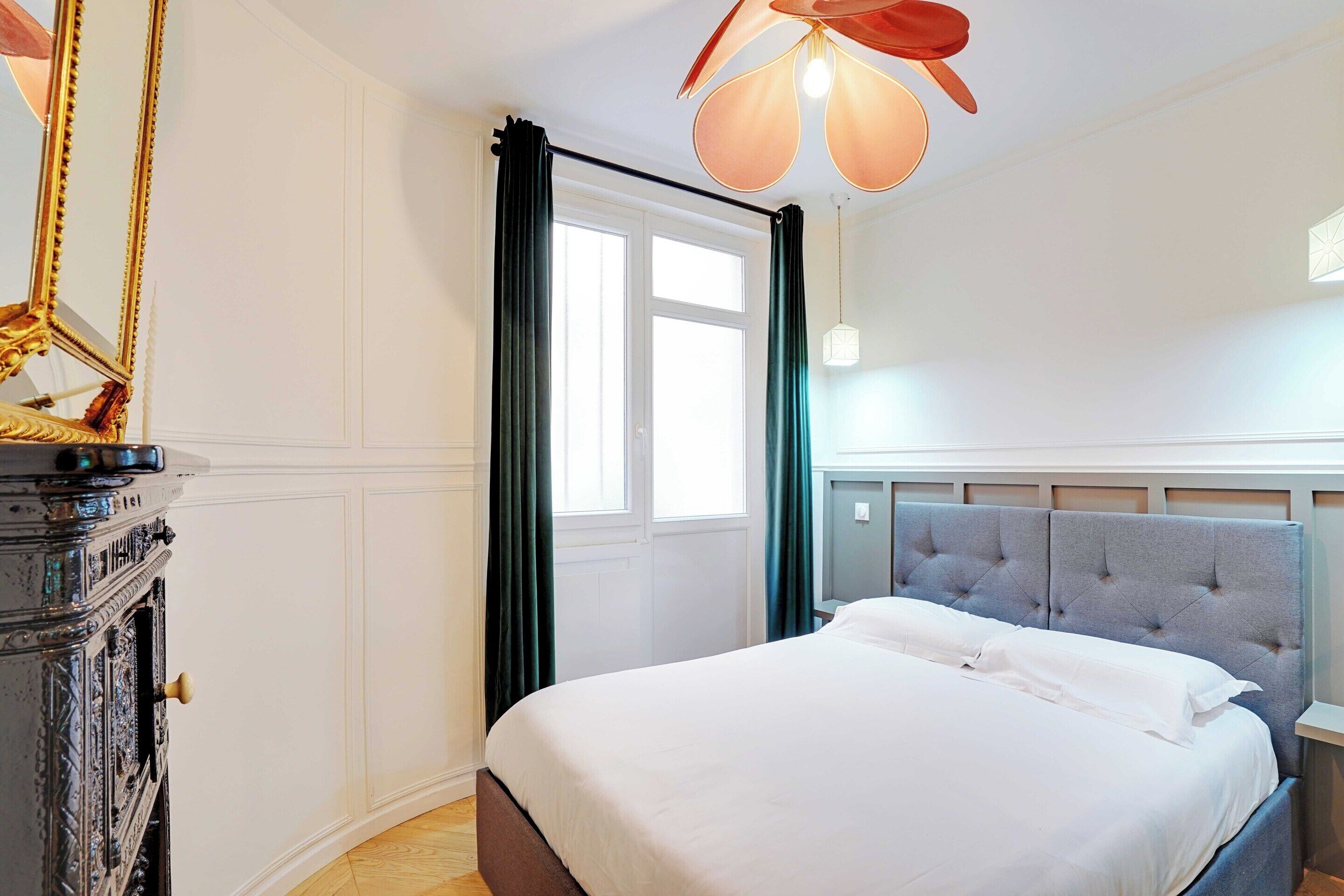 A neatly arranged bedroom with a large bed, a dresser, and a ceiling fan.