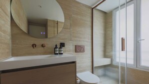 Une salle de bain moderne avec un grand miroir, un lavabo blanc et une cabine de douche en verre.