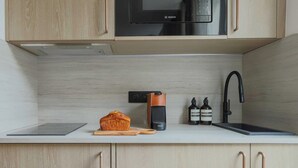 Une cuisine moderne équipée d’un four à micro-ondes Bosch, d’une machine à café et d’un évier.
