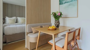 Une chambre d’hôtel moderne comprenant un lit, un canapé, une table à manger et un vase avec des fleurs.