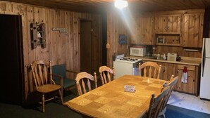 A wooden-paneled room with a dining table and chairs, a microwave, and a refrigerator. - pleasant ridge resort (Menahga)