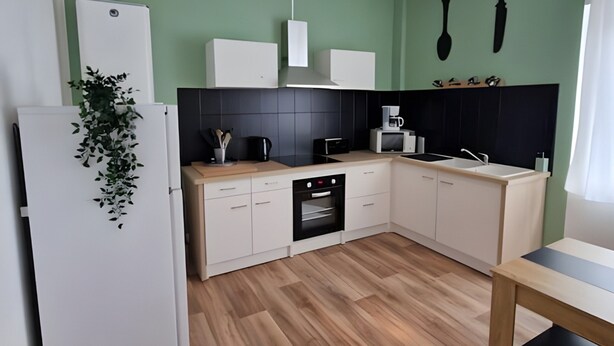 Eine moderne Küche mit weißen Schränken, einer schwarzen Arbeitsplatte und Holzboden.