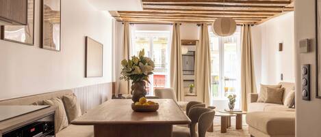 Una sala de estar moderna con una mesa de comedor de madera, sofá y una cocina con horno empotrado.