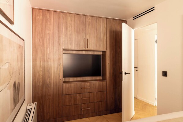 A room with a wooden wardrobe, a flat-screen TV, and a radiator.