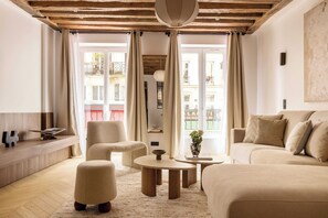 Uma sala de estar moderna com sofá, poltronas, mesa de centro e estante.