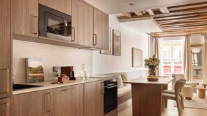 Una cocina moderna con armarios de madera, horno integrado y comedor con mesa y sillas de madera.