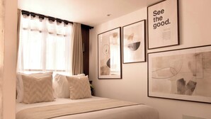 Un dormitorio con cama, cortinas y cuadros en la pared.