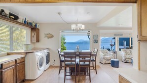 Une cuisine avec vue sur la mer, des meubles en bois, un lave-linge et un coin repas avec des chaises et une table.