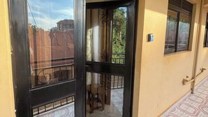 A hotel entrance with a black door, a tiled floor, and a view of the outside. - Kisasi Delight (Kampala)