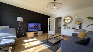 A modern living room with a flat-screen TV, a sofa, a coffee table, and a floor lamp.