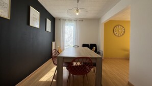 A dining area with a wooden table and chairs, a ceiling fan, and a clock on the wall.