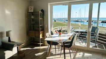 Un comedor con vista a un puerto deportivo, una estantería y una lámpara.
