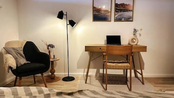 Une pièce comprenant un bureau, une chaise, une lampe et deux tableaux encadrés accrochés au mur.