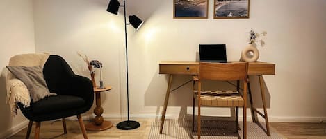 Une pièce comprenant un bureau, une chaise, une lampe et deux tableaux encadrés accrochés au mur.