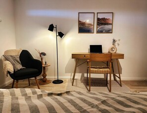 A room with a desk, chair, lamp, and two framed pictures on the wall. - Apartment in Orth (Fehmarn)
