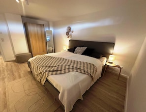 A hotel room with a bed, bedside tables, a mirror, and a wardrobe. - Apartment in Orth (Fehmarn)