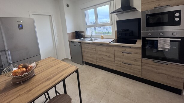 Eine moderne Küche mit einem Edelstahl-Kühlschrank, einer Mikrowelle, einem Backofen und einem Fenster über der Spüle.