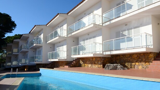 A modern hotel with a swimming pool, stone walls, and balconies with glass railings. - Apartment in Spain Near Sandy Beach (Torroella de Montgrí)