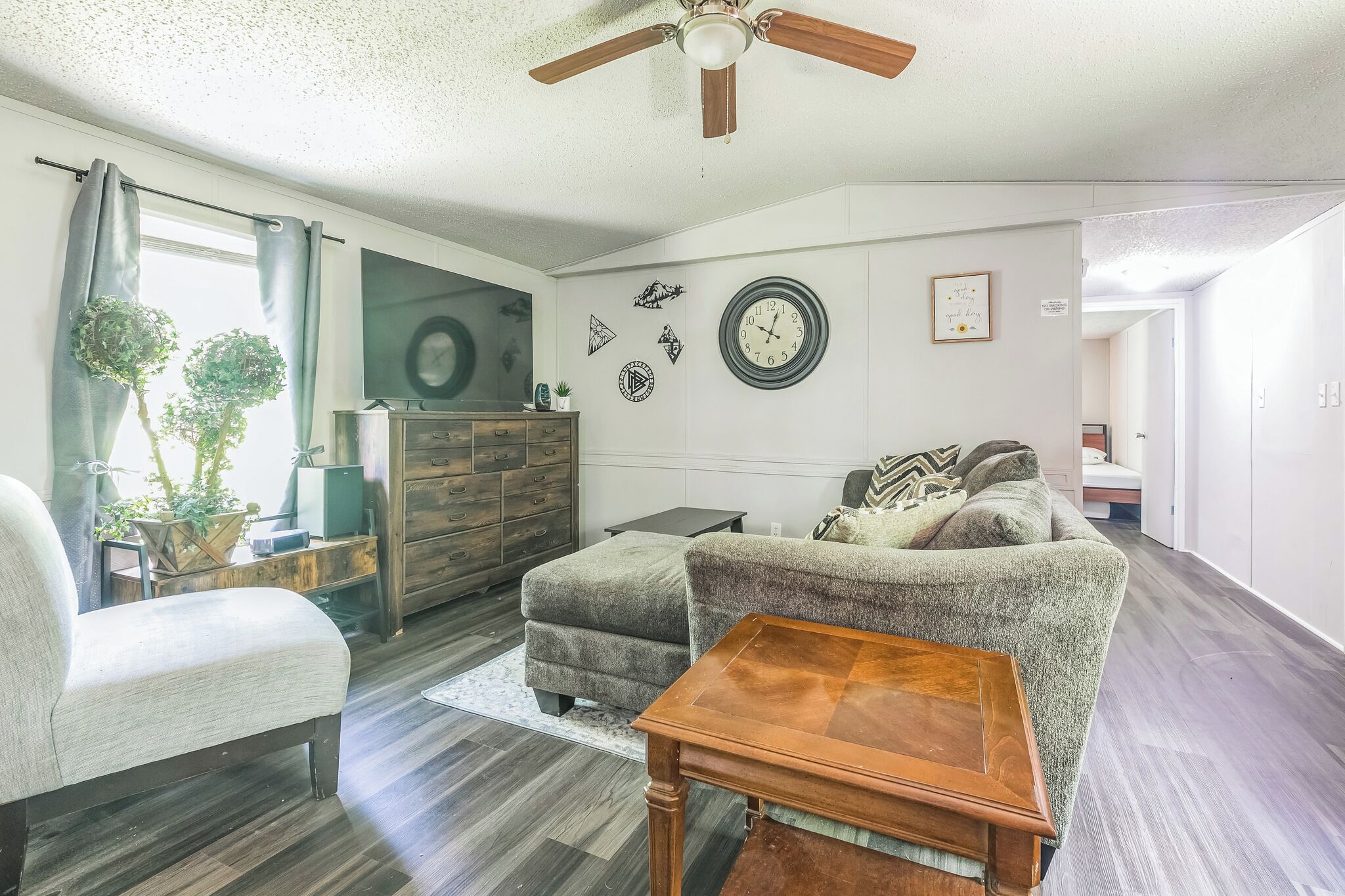 A living room with a ceiling fan, a sofa, a wooden coffee table, a TV, and a dresser.