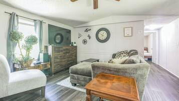 A living room with a ceiling fan, a sofa, a wooden coffee table, a TV, and a dresser.