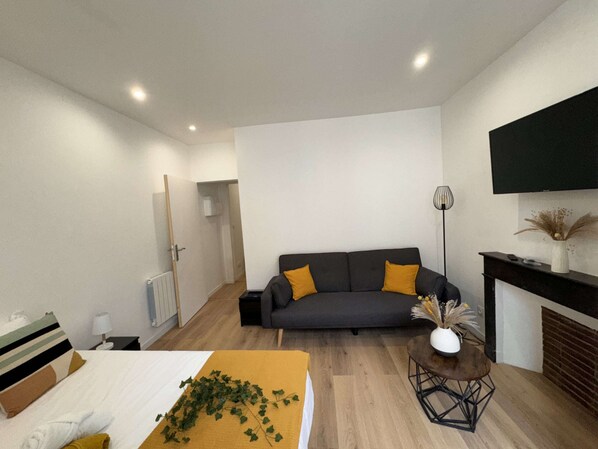 A modern living room with a sofa, a coffee table, a fireplace, and a television mounted on the wall.